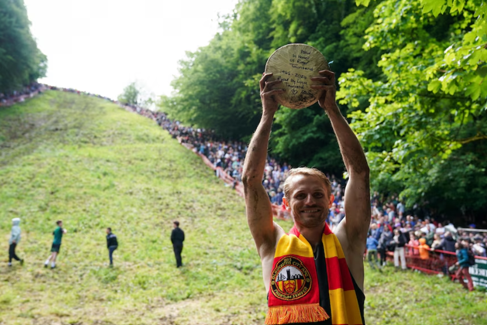 Dylan Twiss with cheese wheel won in Cooper’s Hill Cheese Rolling Race